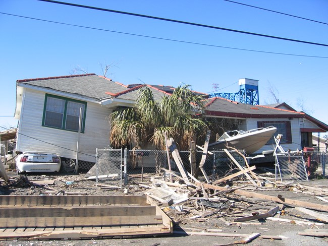 Frame house partially collapsed with tree coming from window