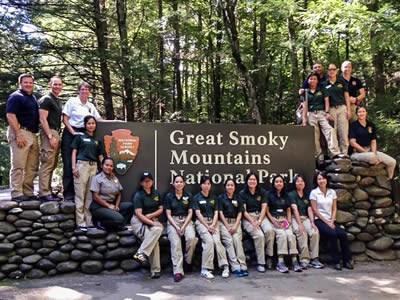 Staff from Great Smoky Mountains National Park and counterparts from Thailand stand in front of the park sign.