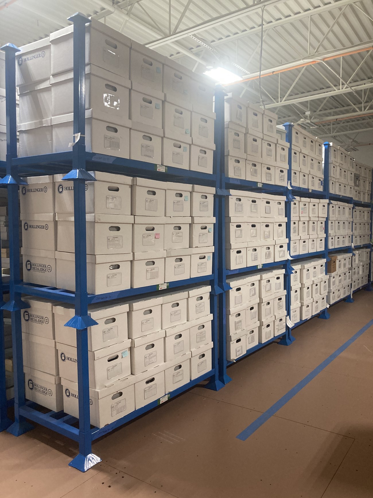 Blue oversized shelves holding white banker's boxes.