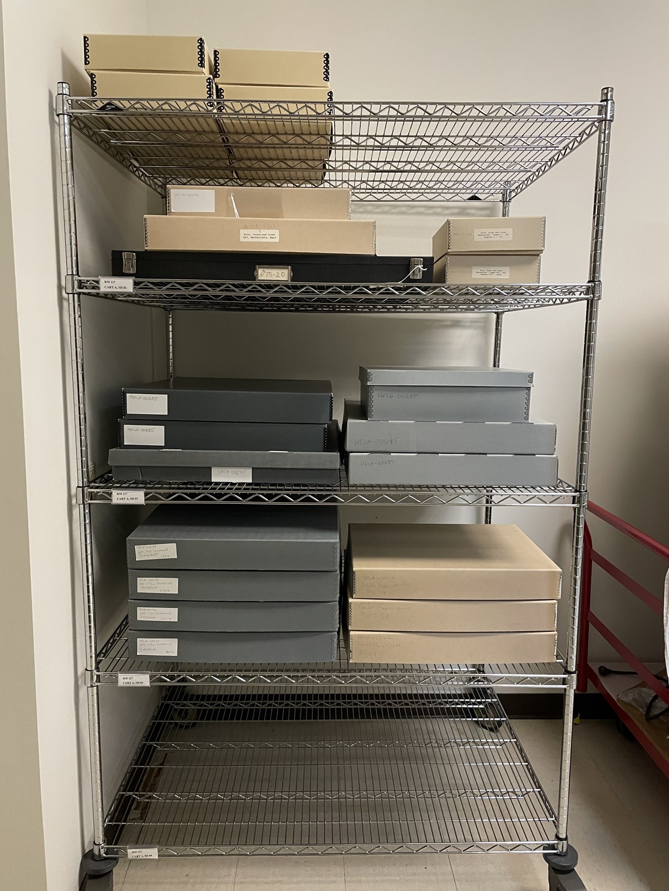 Silver wire shelves holding a variety of archives boxes.