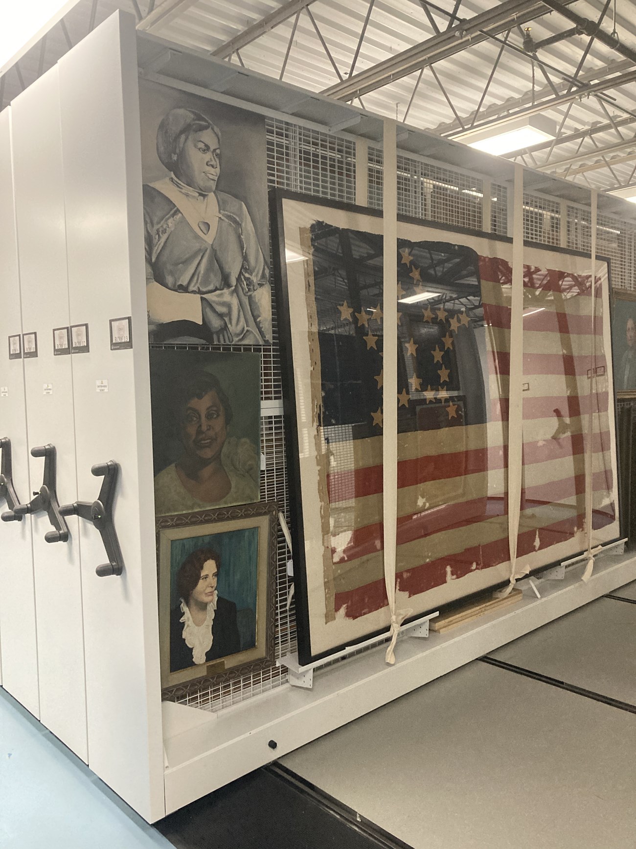 Painting rack holding a large American flag and several paintings.