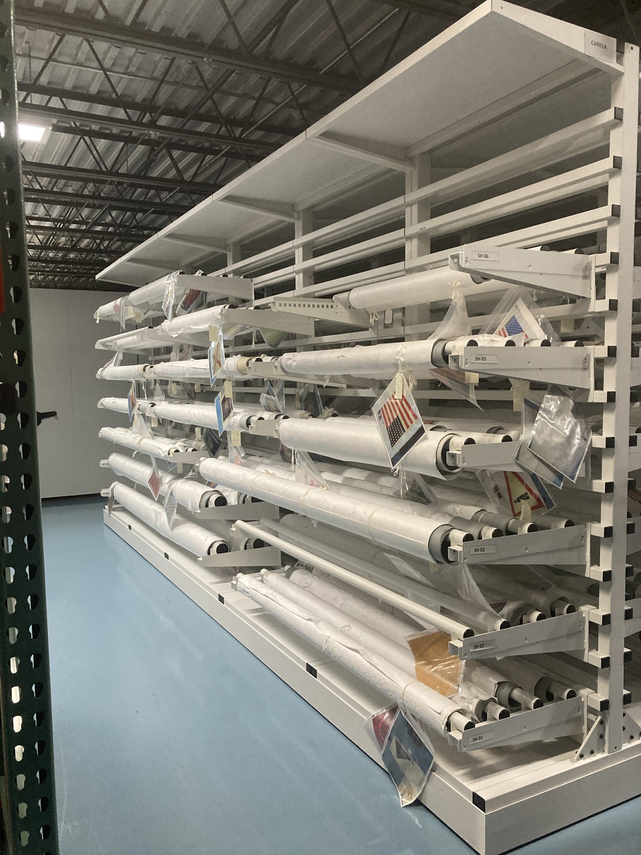 Large cantilever rack holding rolled textiles suspended from the canitlever arms.