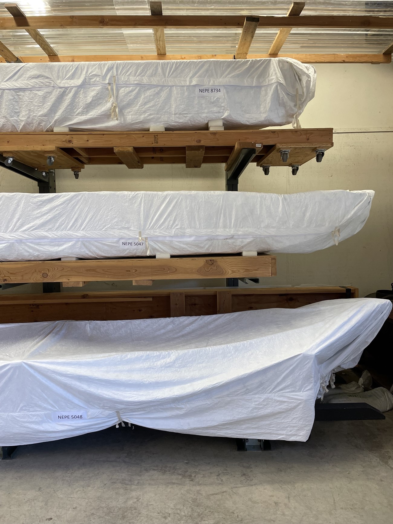 Large cantilever rack holding canoes mounted on mobile pallets.