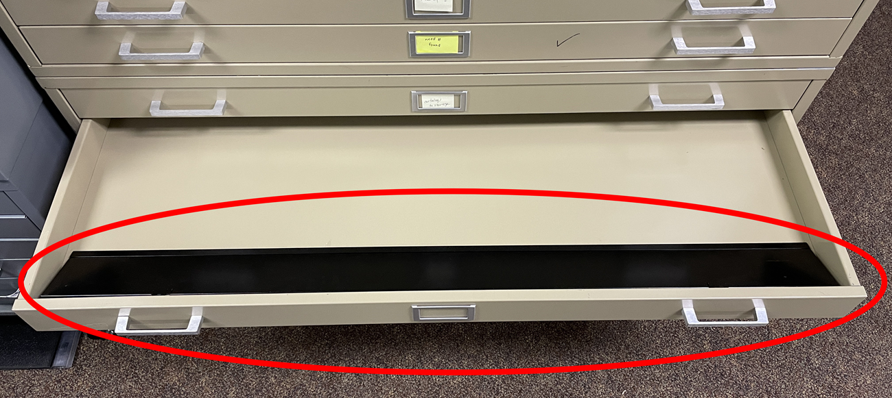 An open flat file drawer with a red circle showing a drawer suppressor inside.