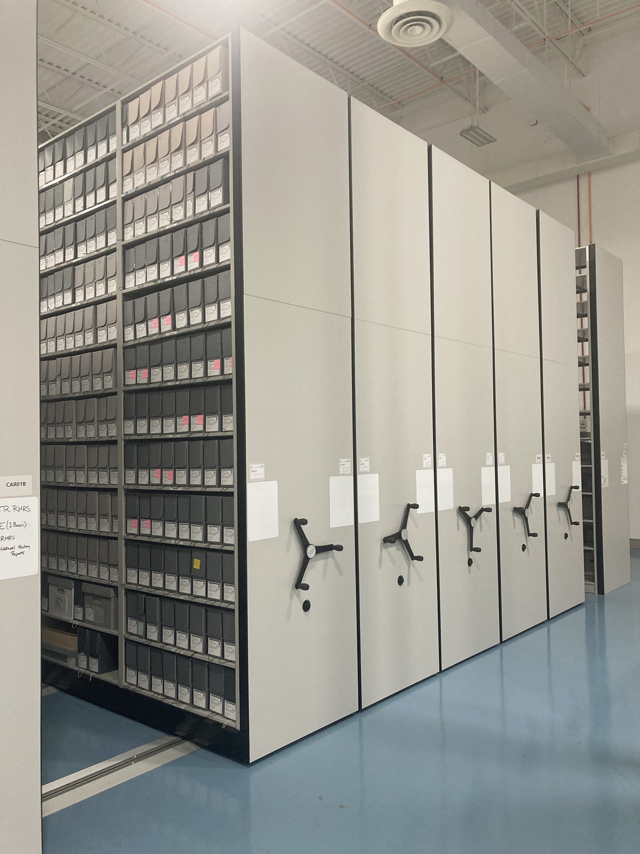 A compact storage unit with 5 carriages holding archives boxes.