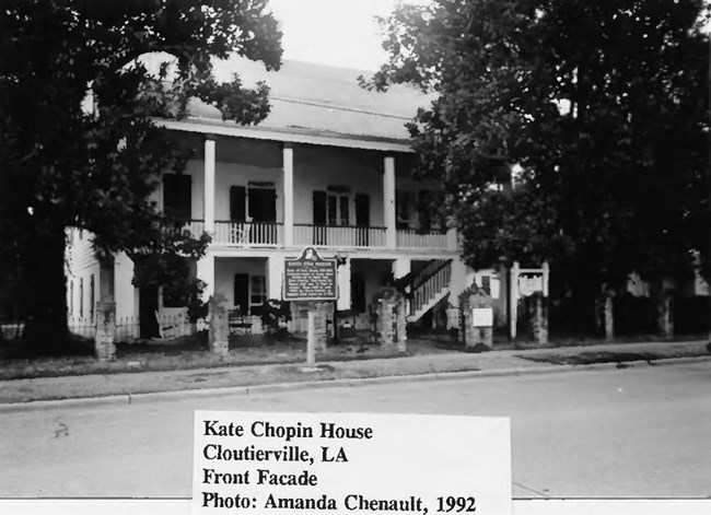 two-story Creole cottage with historic marker on front lawn