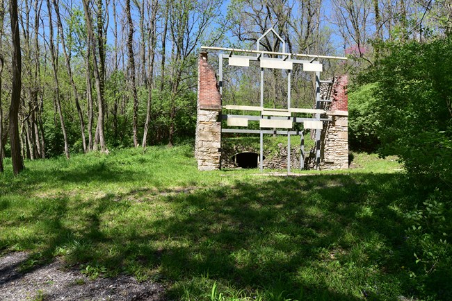 Brewery ruin stabilized with steel structure for interpretation set amid forested area
