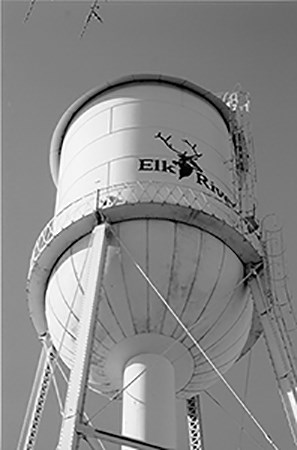 Image of wite water tower with black letters and drawing of elk head.