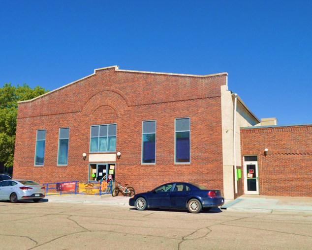 Image of red brick building fronted by concrete pavement.