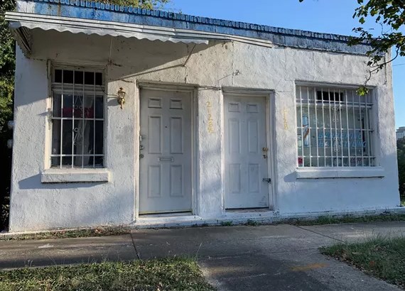 A rectangular, hollow concrete block commercial building with a brick veneer foundation, likely covering concrete block, and a flat roof composed of tar and gravel.