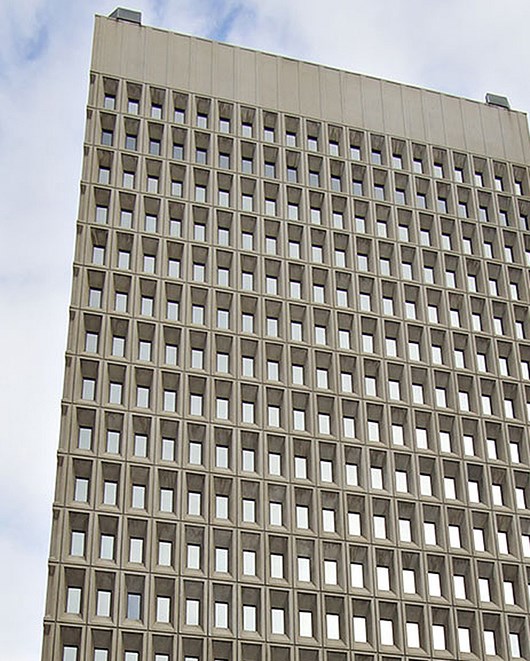Image of portion of tall white building with many windows.