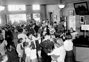 Black and white photo a crowd over 50 of men, women, and children fill the museum lobby.