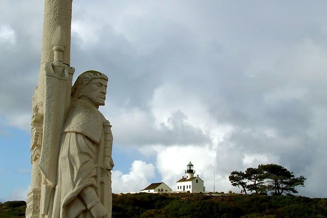 stone monument of Juan Rodriguez Cabrillo with hill and clouds in the background