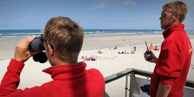 Lifeguard looking at beach with binoculars.
