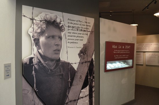 Exhibit inside the National Prisoner of War Museum shows a young man peering through barbed wire