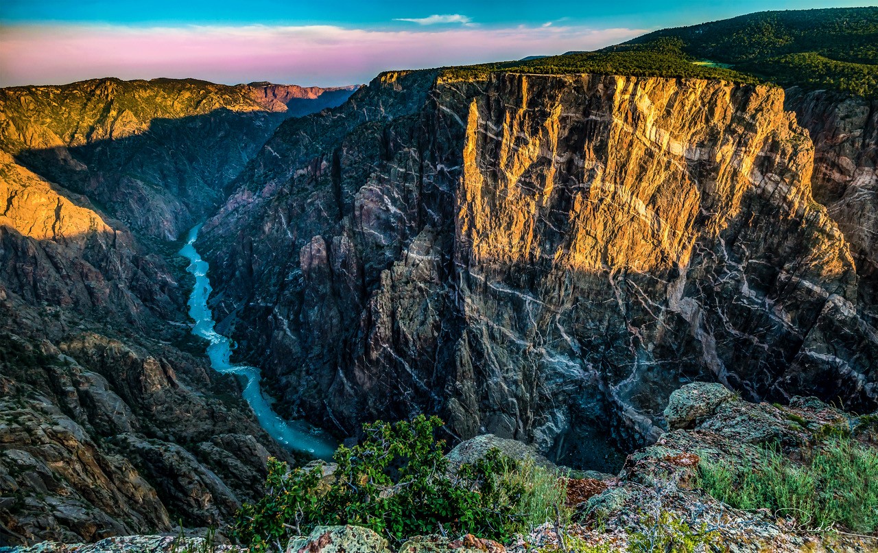 A narrow river flows through a deep, shadowed canyon