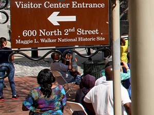 People stand under the entrance sign to Maggie L Walker National Historic Site