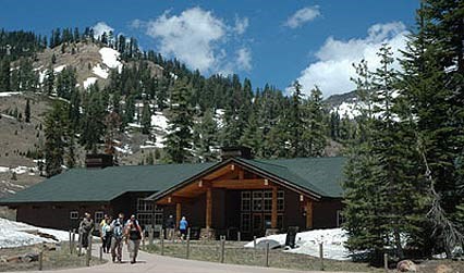 Visitors exiting the Kohm Yah-mah-nee Visitor Center, surrounded by snow spotted mountains.