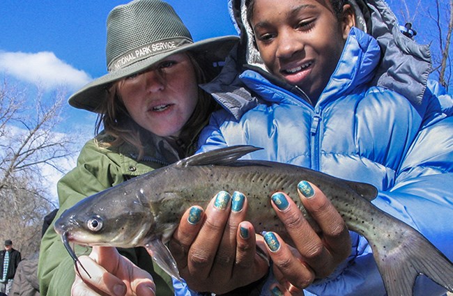 girl holds fish as ranger describes it