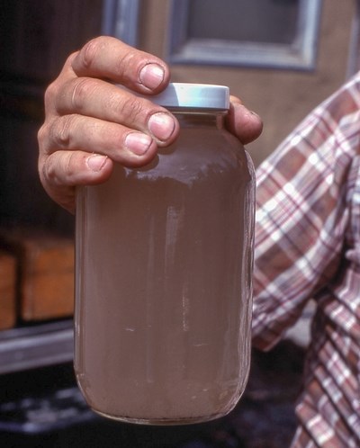 Man holding jar filled with brown tinted water