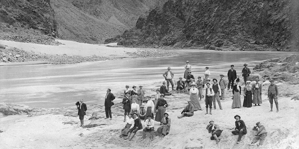 historic black and white photo of people standing next to the Colorado River at Grand Canyon National Park