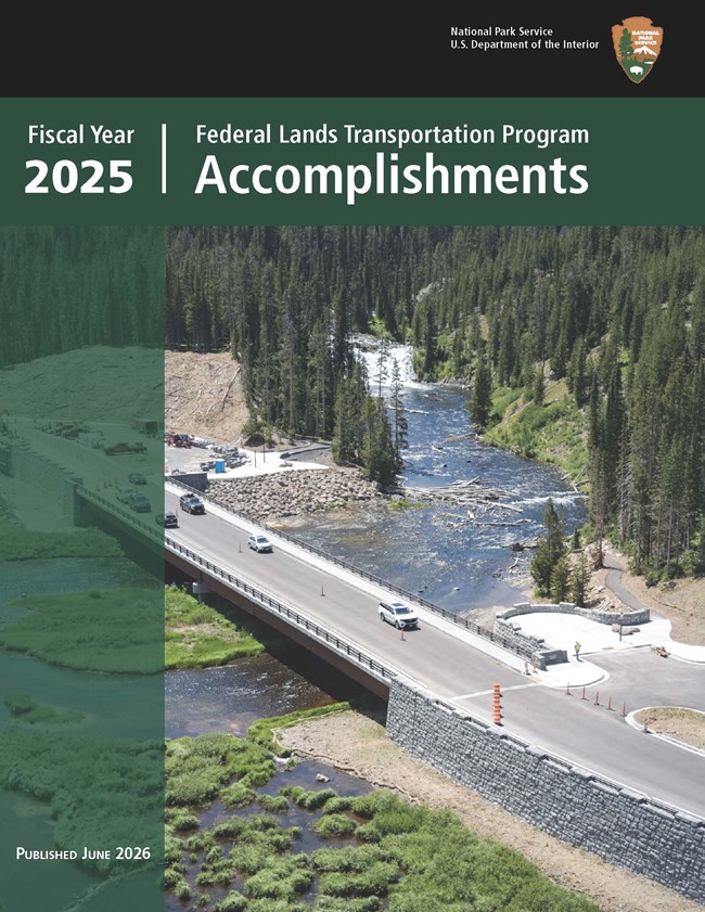 river that curves through hillsides covered in evergreen trees. Orange construction barriers bar access to one of the two lanes and a turnoff from the bridge, and at the opposite end of the bridge is a parking lot with multiple parked vehicles.  Two-lane