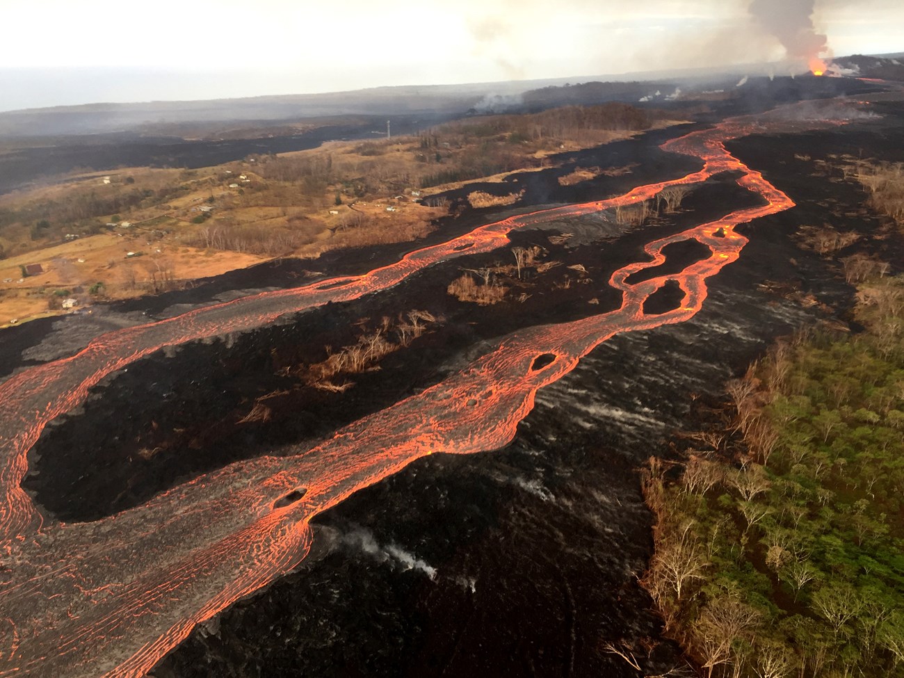Aerial photo of molten lava flowing across a landscape