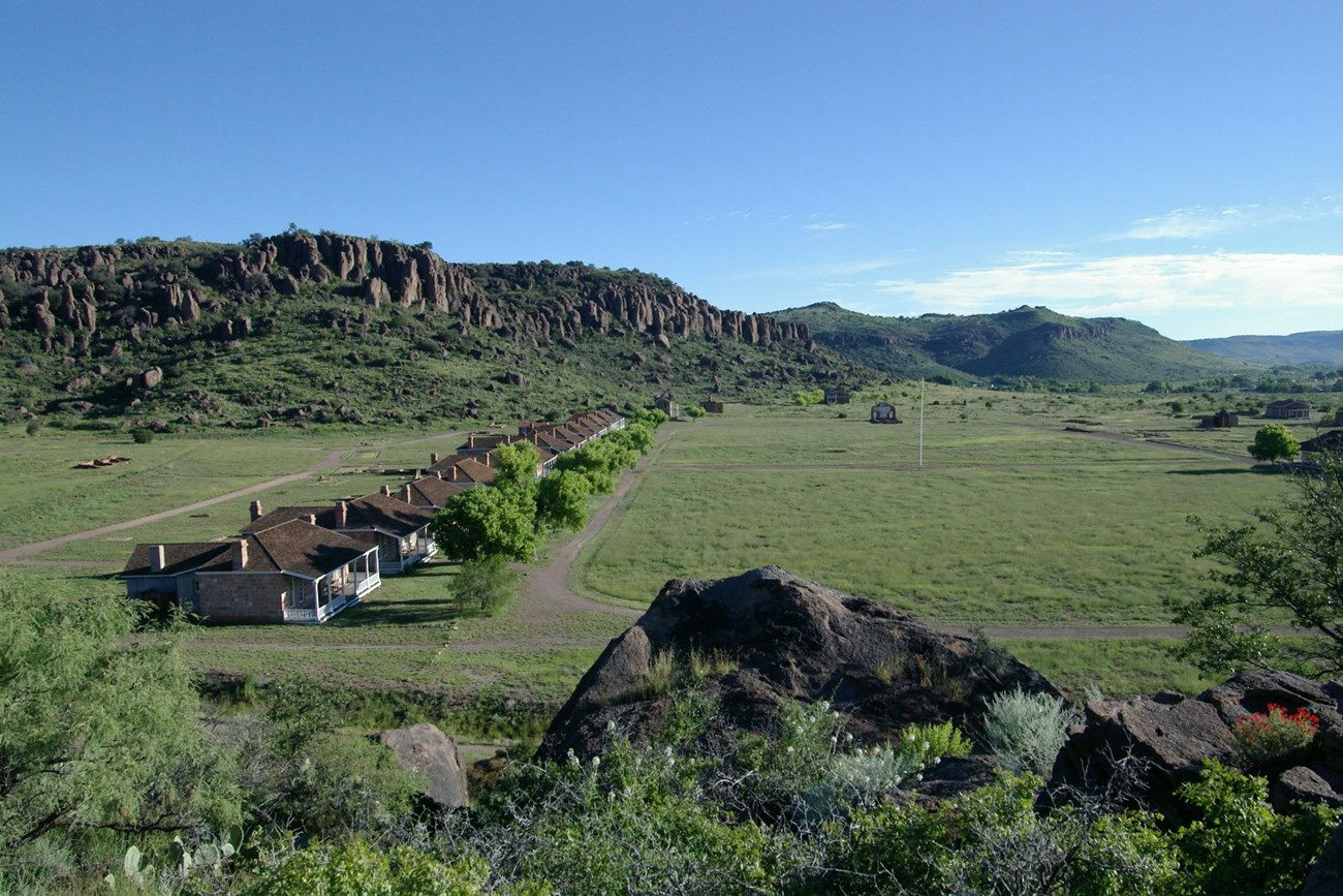 photo of a row of buildings in a valley with cliffs in the distance