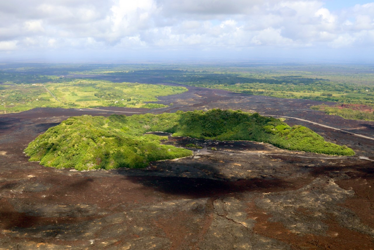 Photo of areas of barren lava flows surrounding islands of older vegetation.