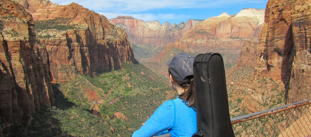 A person wearing an instrument in a backpack stands at a geologic overlook.