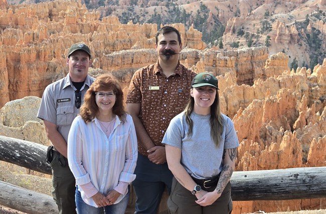 Four people stand in front of a geologic overlook.