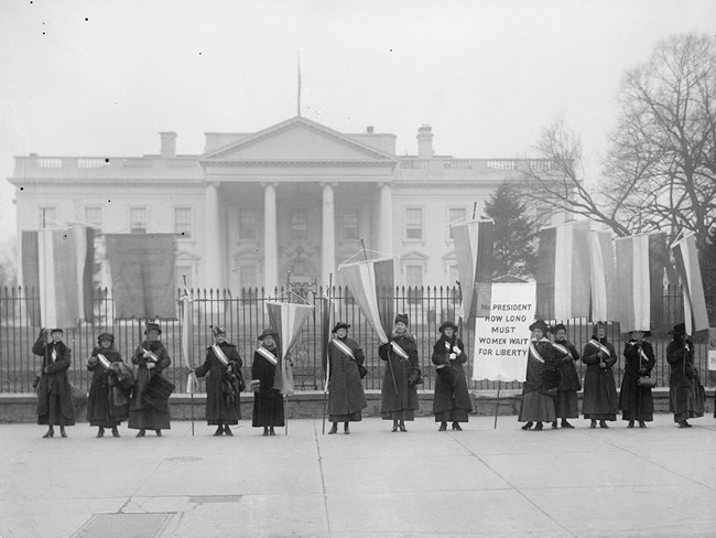 Group of women holding protest signs in front of the White House