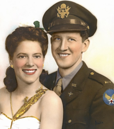 man and women sitting for portrait during world war ii. man is in army uniform, woman is in formal dress.