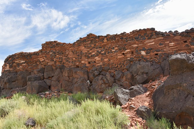 Pueblo wall built of alternating layers of red sandstone and black basalt rocks
