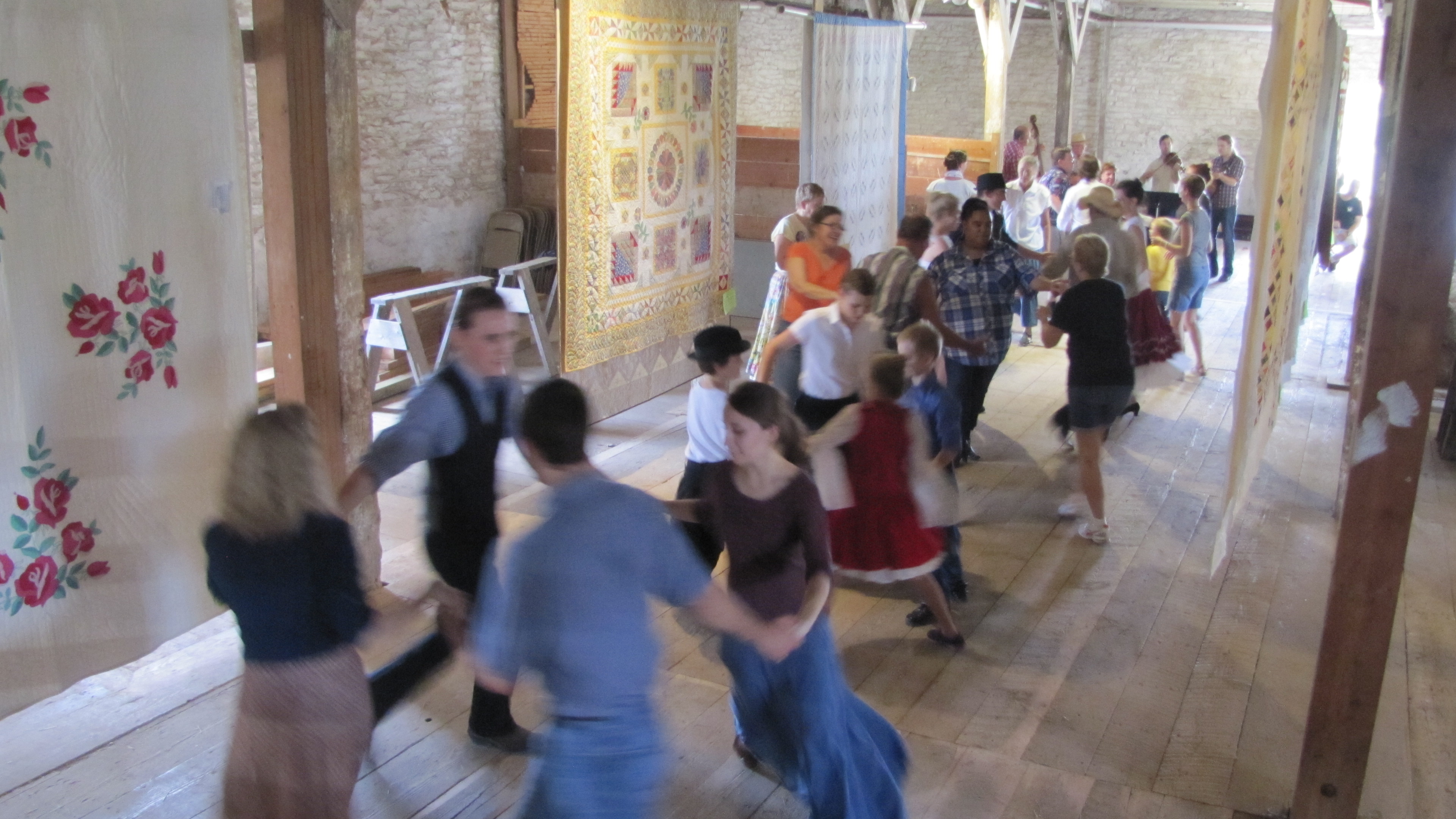 Dancers enjoy an old-fashioned barn dance among the quilts.