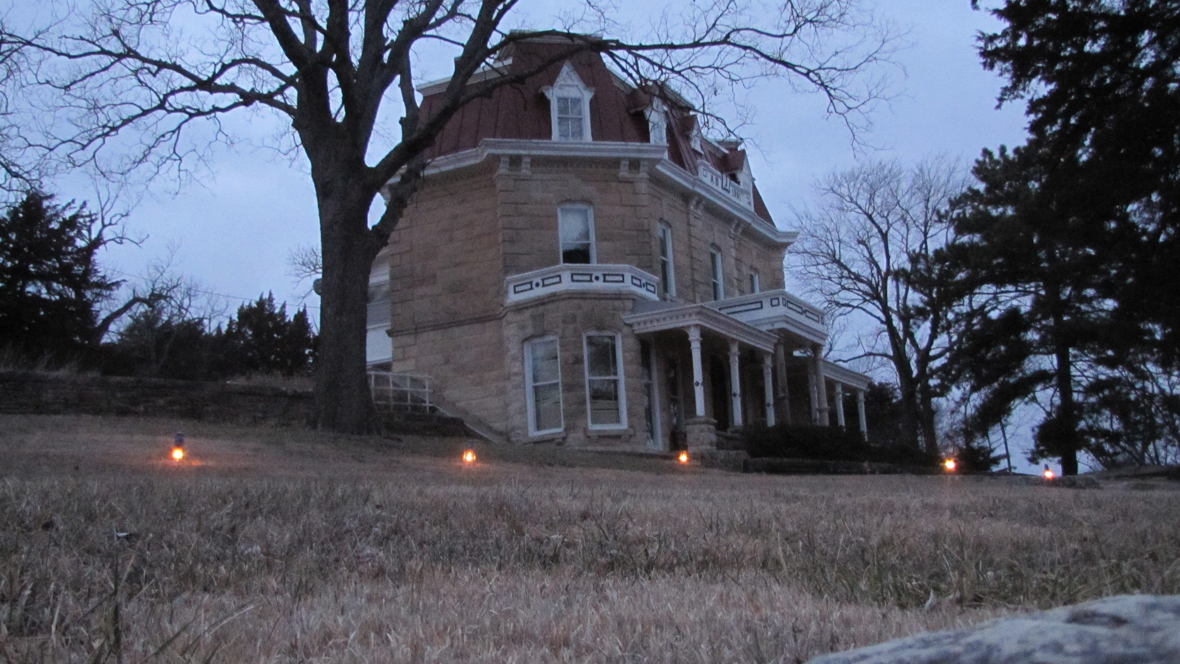 Historic 3-story limestone mansion with lanterns lighting the pathway during the candlelight tours