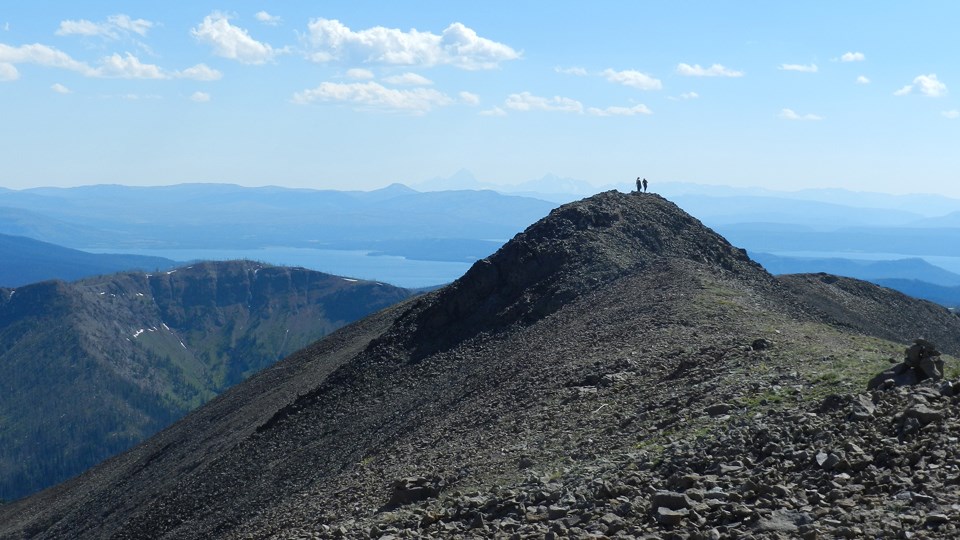 Two hikers standing on the rocky summit of Avalanche Peak