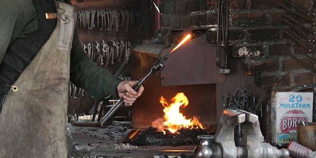 Park Ranger holds hot iron near the forge during a demonstration.
