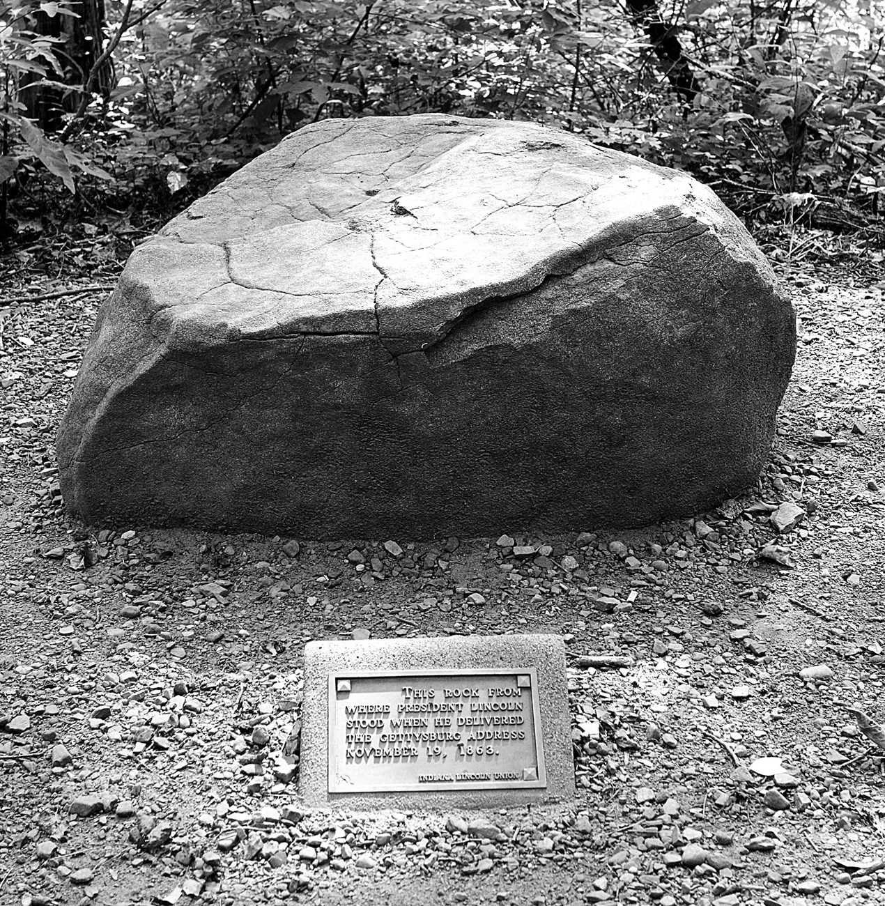 Large stone on side of trail with plaque in front