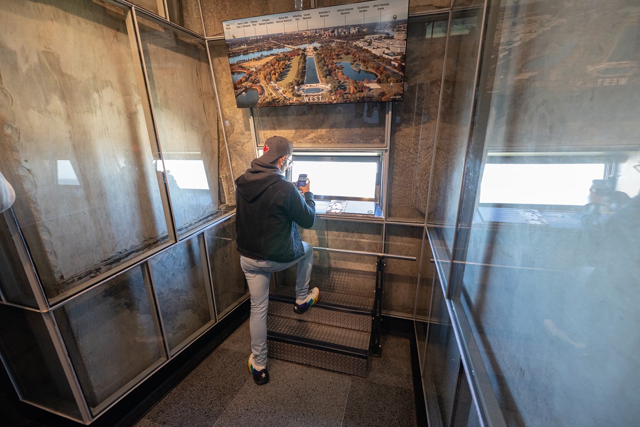 A man takes a photo from a rectangular window inside the Washington Monument.