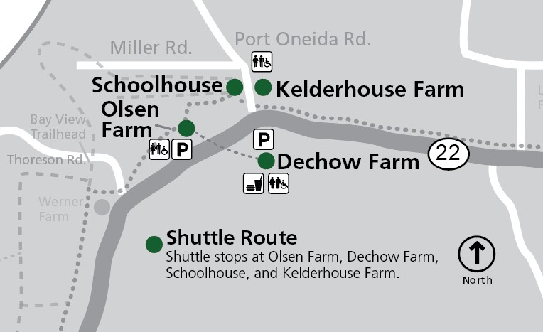 This map shows the Port Oneida area within Sleeping Bear Dunes National Lakeshore, focusing on shuttle stops and historic farm sites along M-22. The map is oriented with north at the top, as indicated by a compass rose. The primary road, M-22, runs horizo