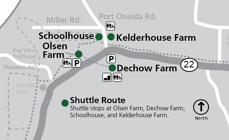 This map shows the Port Oneida area within Sleeping Bear Dunes National Lakeshore, focusing on shuttle stops and historic farm sites along M-22. The map is oriented with north at the top, as indicated by a compass rose. The primary road, M-22, runs horizo