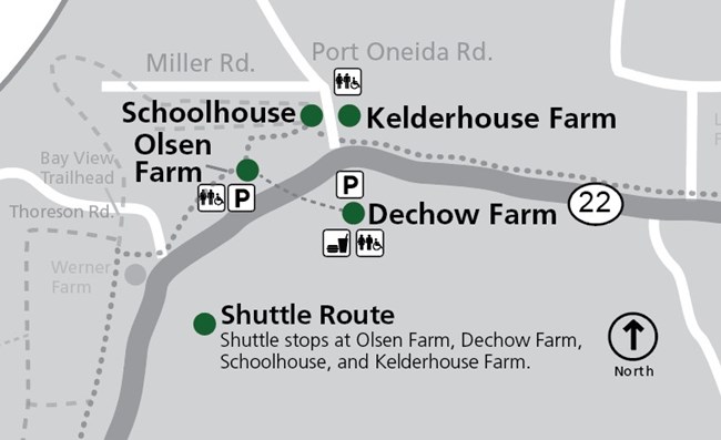 This map shows the Port Oneida area within Sleeping Bear Dunes National Lakeshore, focusing on shuttle stops and historic farm sites along M-22. The map is oriented with north at the top, as indicated by a compass rose. The primary road, M-22, runs horizo