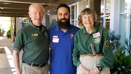 Park Ranger and two Trails and Rails volunteers standing together and smiling outside of a classroom for their photo to be taken.