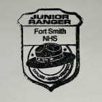 An ink stamp of a badge with a flat hat and the text, "Junior Ranger, Fort Smith NHS."