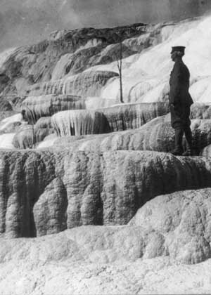 A US Army soldier stands on the Mammoth Hot Springs terraces, watching over Pulpit Spring