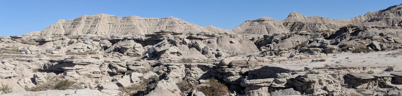 a vast landscape of eroded buttes, layered with more resistant sandstone boulders.
