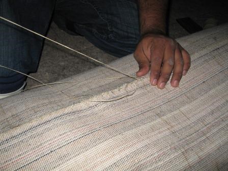 Hand-sewing of carpet sections.