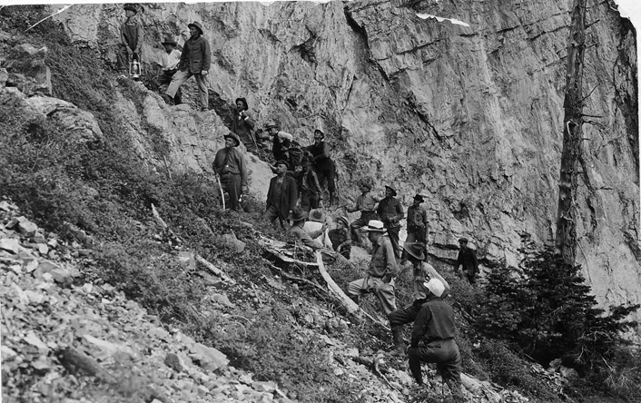 Multiple people walking up a steep mountain side