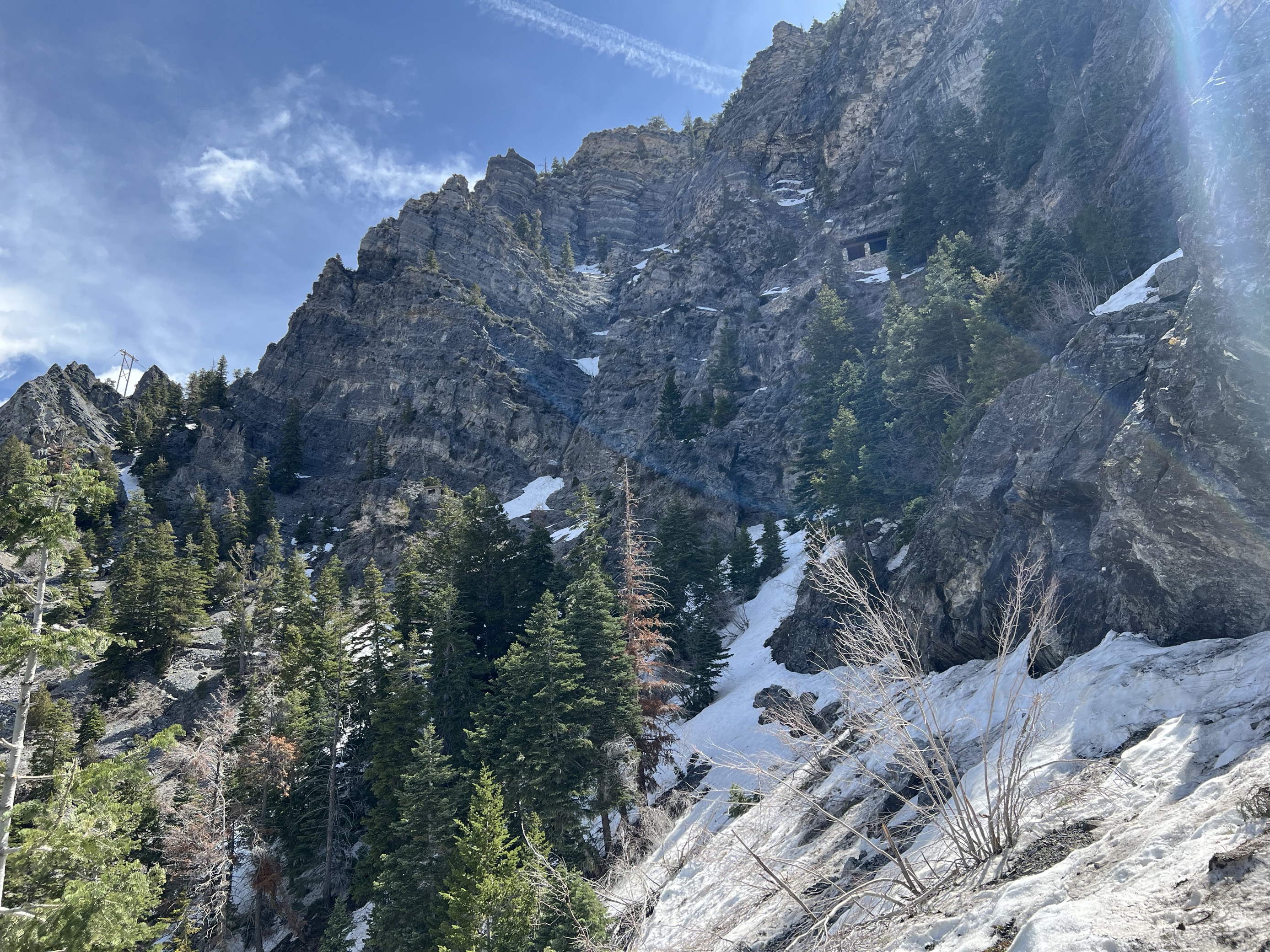 Snow covering a mountainside with a small, stone building visible.